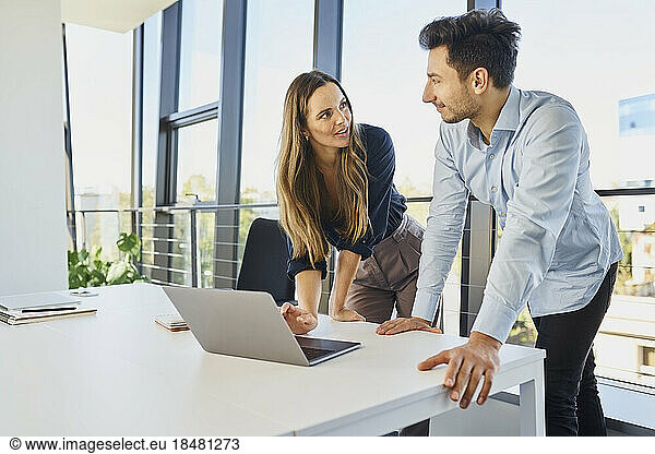 Businesswoman with laptop discussing by colleague at office