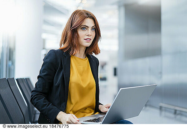 Businesswoman with laptop sitting on chair