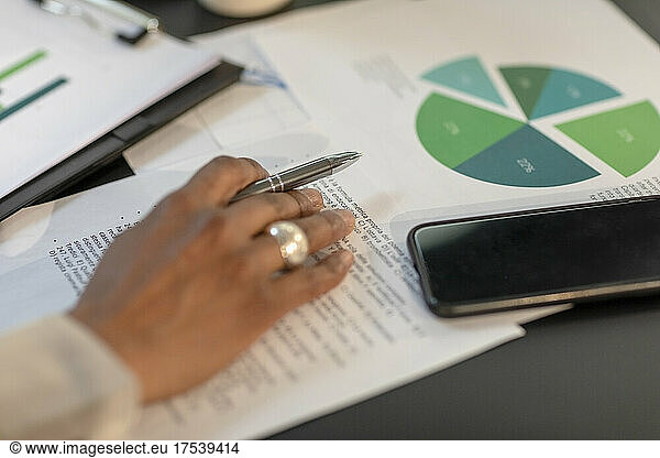 Businesswoman with paper document and smart phone at table