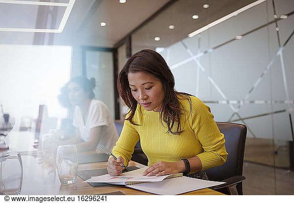Businesswoman with paperwork in conference room meeting