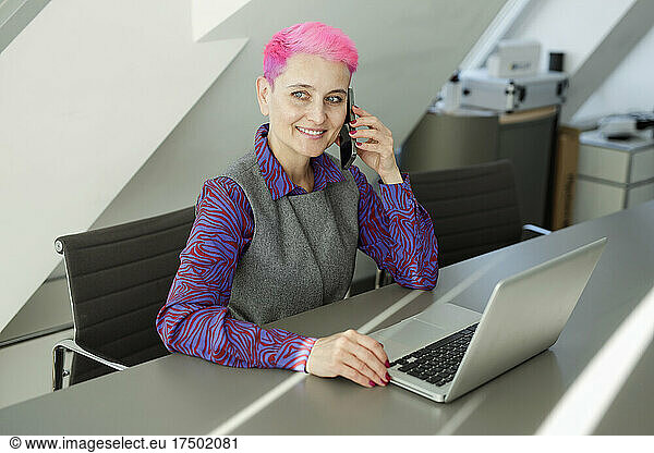 Businesswoman with short hair talking on mobile phone in office