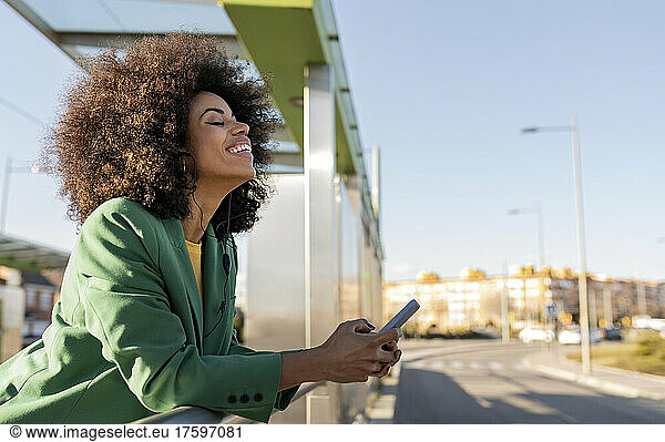 Businesswoman with smart phone leaning on railing