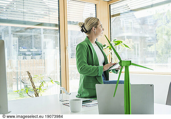 Businesswoman with tablet PC sitting on desk in office