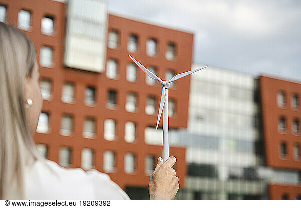 Businesswoman with wind turbine model in front of building