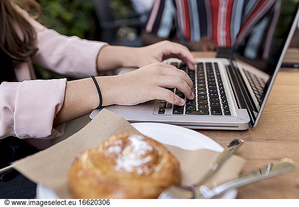 Businesswoman working on laptop at table in cafe