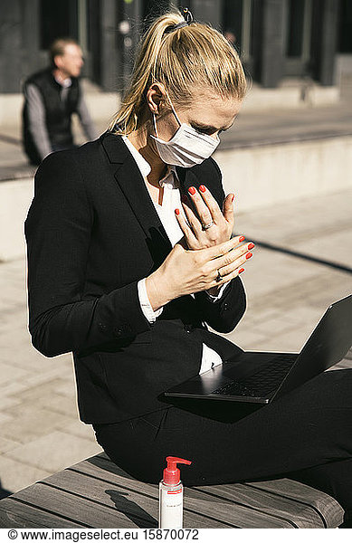 Businesswoman working with laptop waring face mask and hand sanitizer
