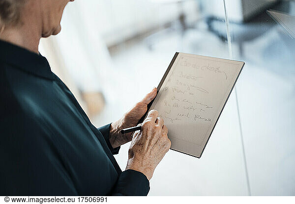 Businesswoman writing on note pad in office
