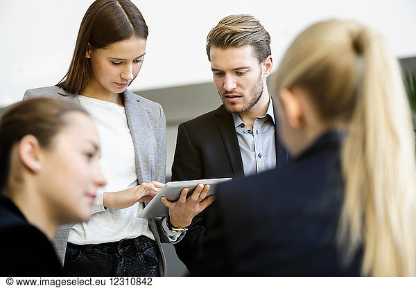 Businesswomen and man in office meeting using digital tablet  over shoulder view