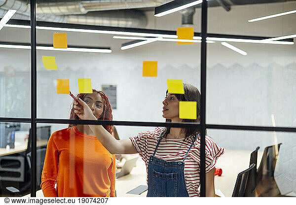Businesswomen discussing over adhesive notes in office