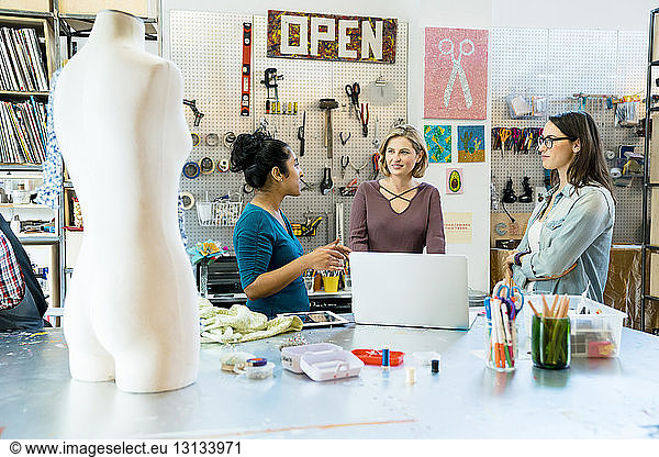 Businesswomen discussing while standing by work bench