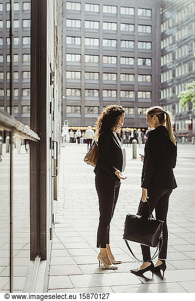 Businesswomen talking while standing by building