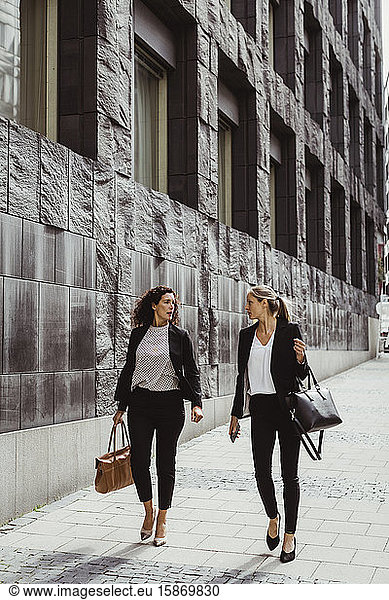 Businesswomen talking while walking by building