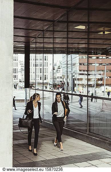 Businesswomen talking while walking on footpath