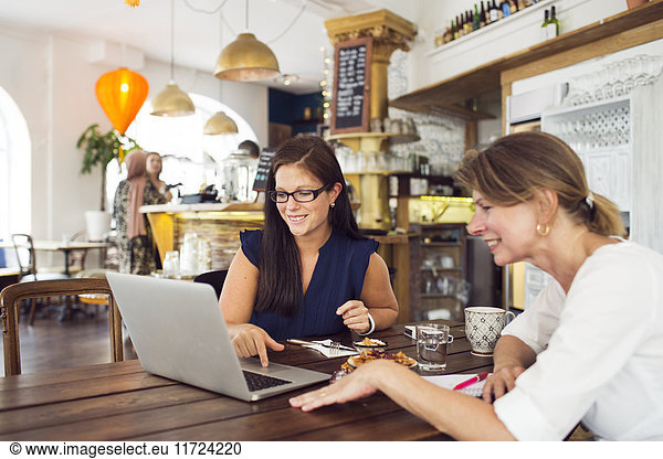 Businesswomen using laptop during lunch in restaurant