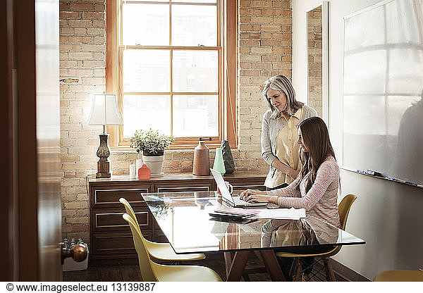 Businesswomen using laptop in board room