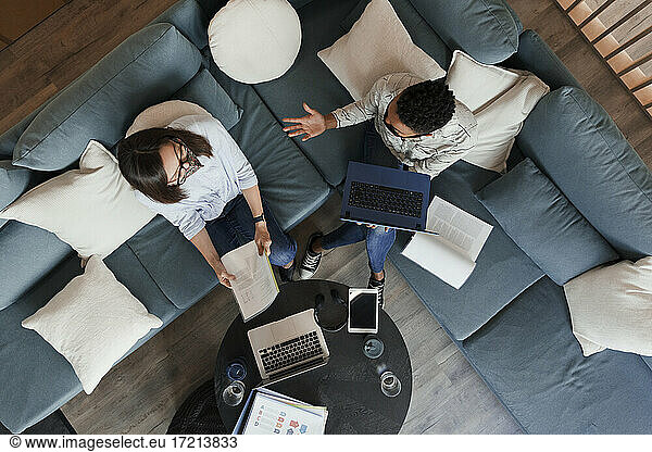 Businesswomen with laptops and paperwork meeting on office sofa