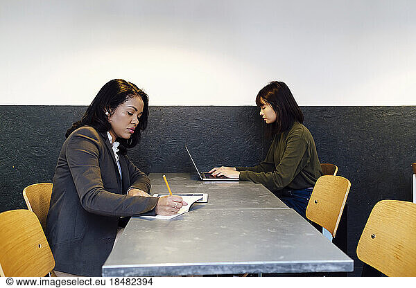 Businesswomen working together sitting at desk in office