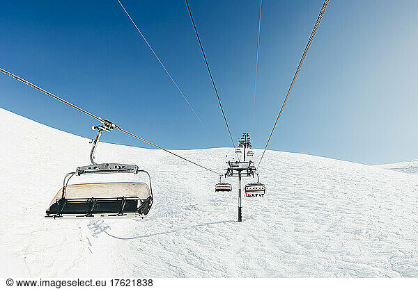 Cable cars on snow covered mountain on sunny day