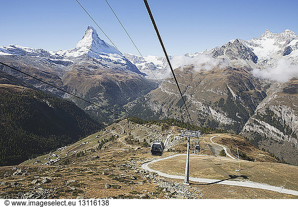 Cable cars over mountain against clear blue sky