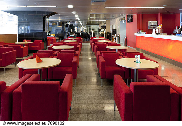 Cafe and bar area in Tallinn airport. Red seats and small circular tables. Passenger facilities.