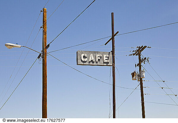 Cafe sign high on a pole  electricity and telephone wiring on posts.