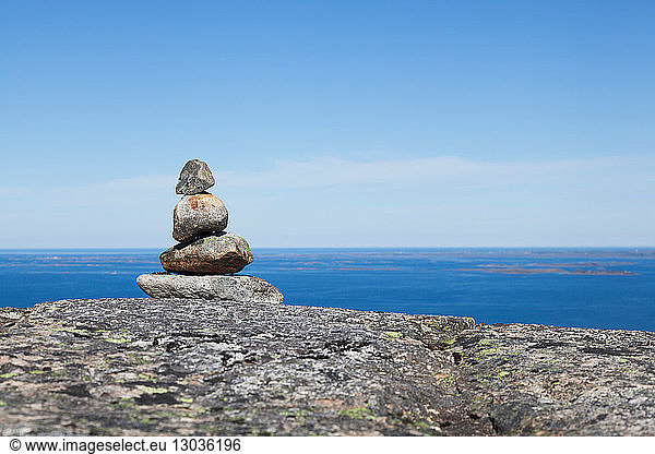 Cairn on top of rock formation with inlet and blue sky  Aure  More og Romsdal  Norway