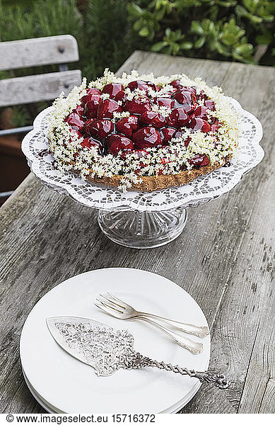 Cake stand with homemade strawberry cake decorated with elderflowers