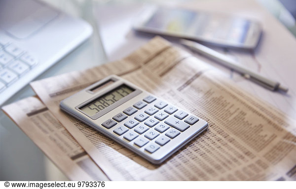 Calculator close up newspaper and pen on desk