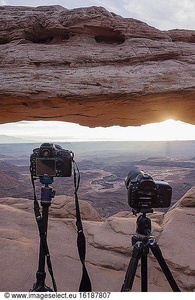 Cameras with view through Mesa Arch at sunrise  Colorado River Canyon with La Sal Mountains in the back  view at Grand View Point Trail  Island in the Sky  Canyonlands National Park  Utah  USA  North America