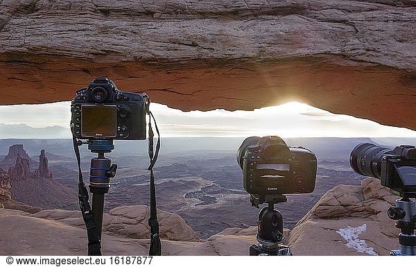 Cameras with view through Mesa Arch at sunrise  Colorado River Canyon with La Sal Mountains in the back  view at Grand View Point Trail  Island in the Sky  Canyonlands National Park  Utah  USA  North America