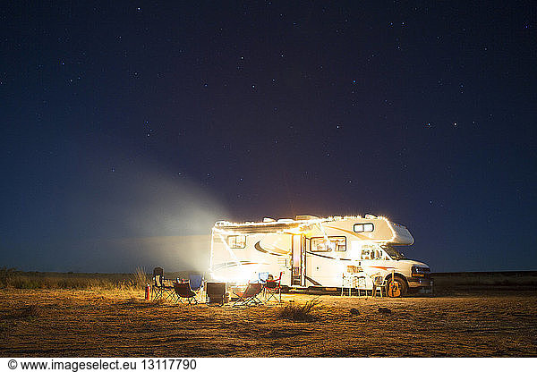Camper van on field against sky during night