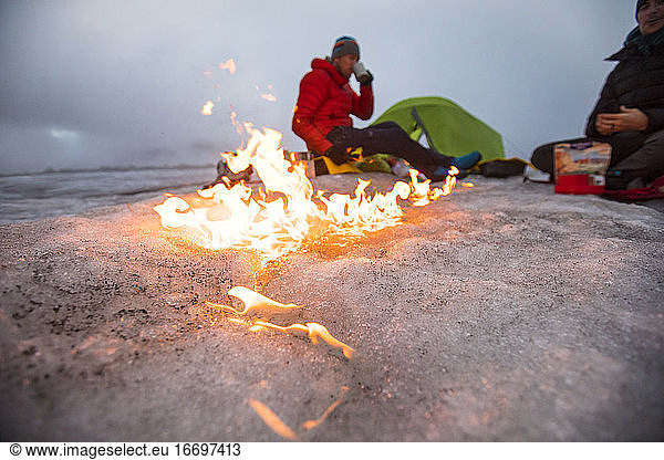 Campfire moves across the glacier as two men camp on a glacier.