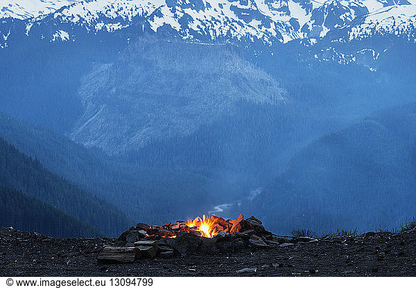 Campfire on field against snowcapped mountains