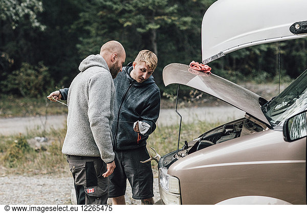 Canada  British Columbia  two men checking oil level of minivan