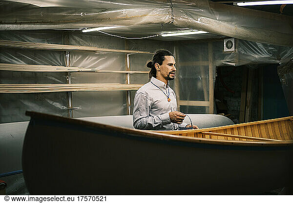 Canoe builder at workshop next to the boat  small business and craft