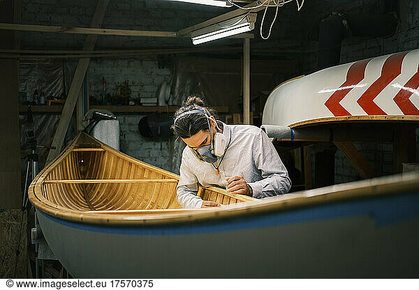 Canoe builder sanding the boat at a small garage workshop