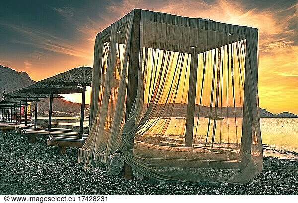 Canopy for beach loungers with curtains and parasols  sunrise  beach  Rhodes  Greece  Europe