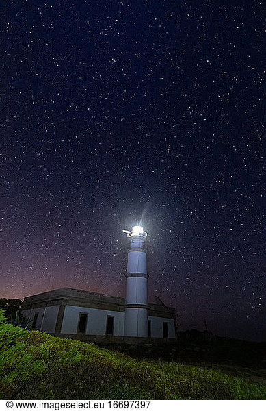 Cap Salines lighthouse in Mallorca (Spain) shining on a starry night