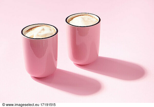 Cappuccino in rosa Tassen auf rosa Hintergrund