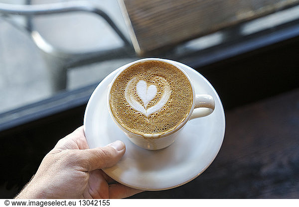 Cappuccino mit Herzform-Kunst in der Hand