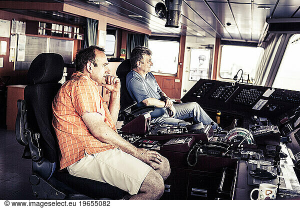 Captain and first officer sitting at the navigation deck onboard a container ship.