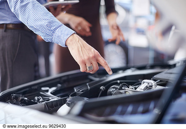 Car dealer explaining car engine