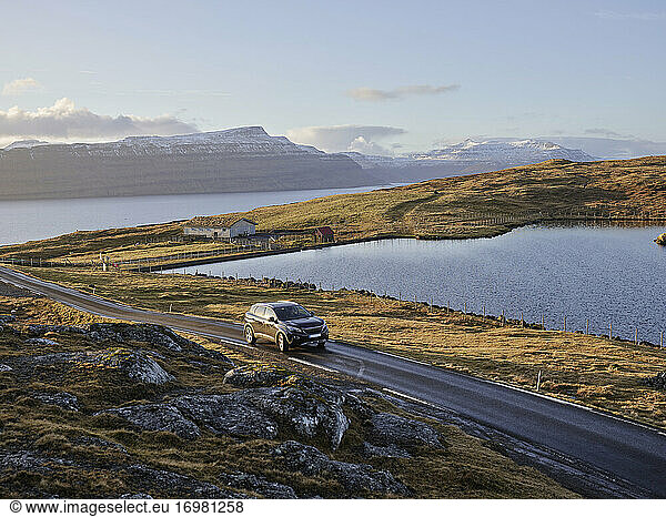 Car driving along country road at sunset in the Faroe Islands