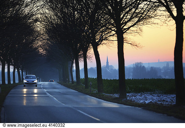 Car driving down a country road at sunset in wintertime near Duisburg  North Rhine-Westphalia  Germany  Europe