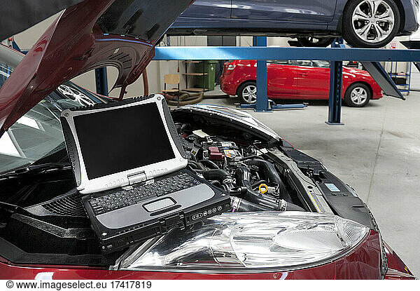 Car in a workshop  a computer running diagnostics on the engine.
