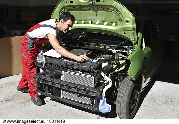 Car mechanic examining accident damaged car before repair