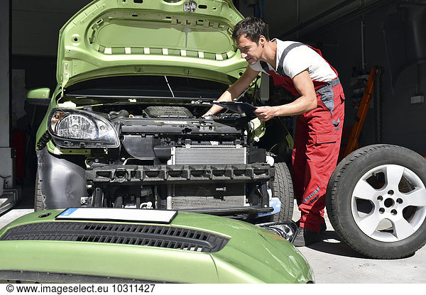 Car mechanic examining accident damaged car before repair
