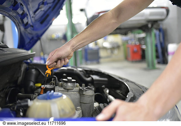 Car mechanic in a workshop checking motor oil