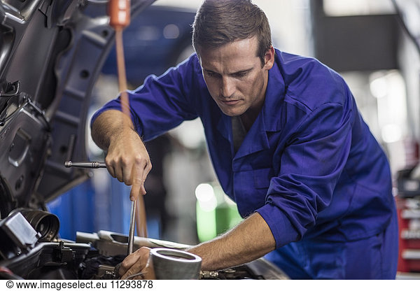 Car mechanic in a workshop repairing car
