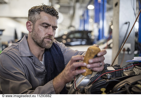 Car mechanic in a workshop using diagnostic equipment
